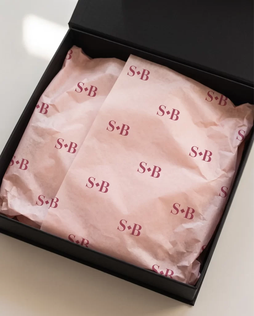 Roze zijdepapier met het S·B monogram van Society Beauty in een zwarte doos