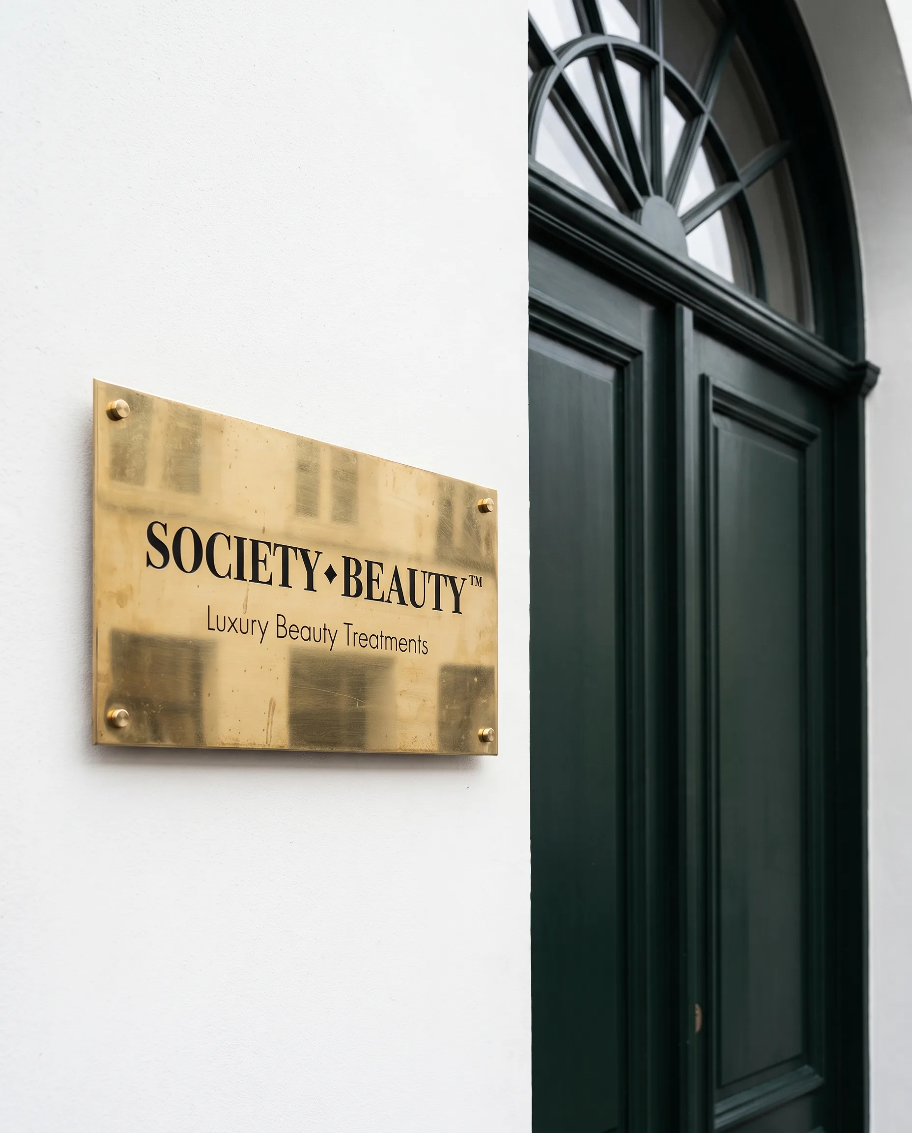 Messing naamplaat van Society Beauty naast een groene voordeur