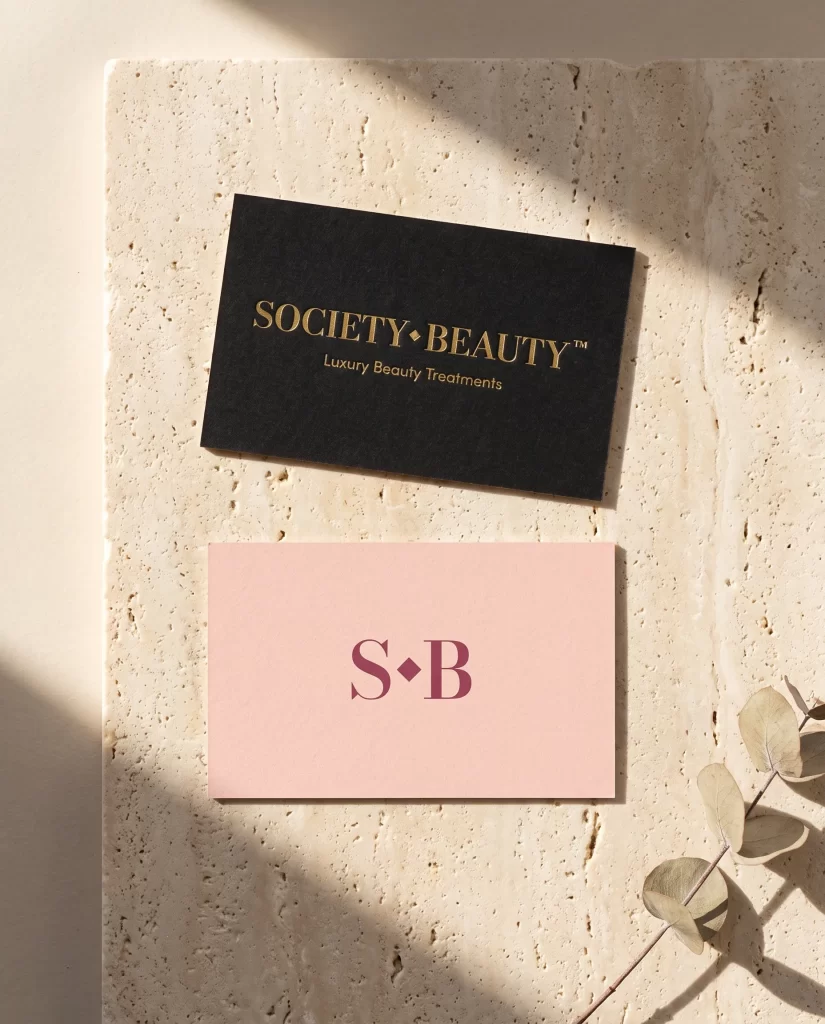 Zwart en roze visitekaartje van Society Beauty met logo en S·B monogram op travertin